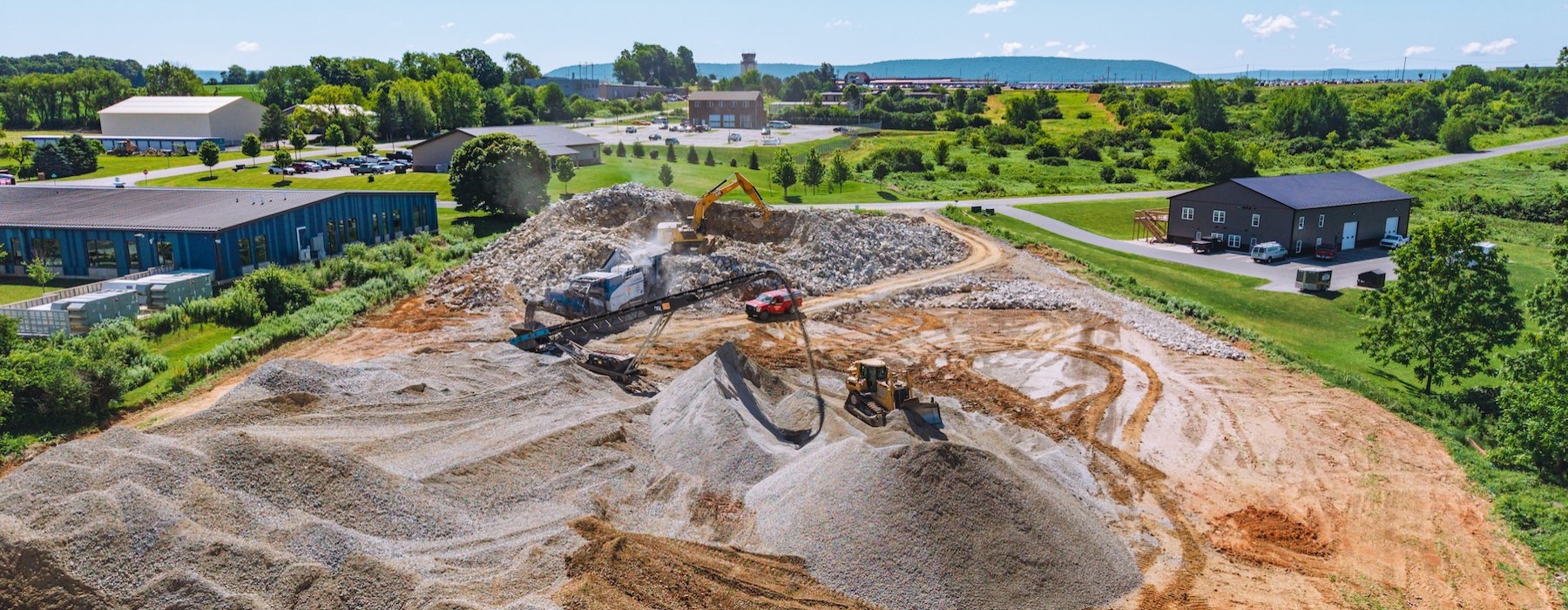 a dirt hill with a hole in it and buildings in the background